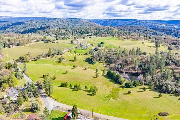 Aerial view of green pastures and wooded foothills